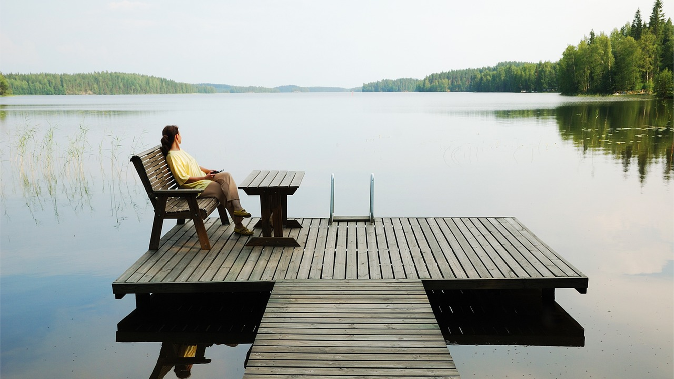 Mujer sentada frente a un lago tranquilo reflexionando sobre la promesa de Dios