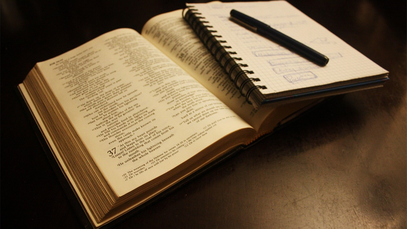 Biblia abierta junto a un cuaderno de notas